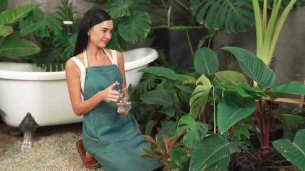 Молодая Женщина Садовница Ухаживает Тропическим Растением Нежно Поливает Минималистском Архитектурном — стоковое видео