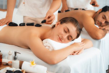 Lüks tatil köyündeki kaplıca salonunda sıcak taş masajı. Gündüz dinginliği ortam, mutlu çift müşterileri bazalt taşı masajının keyfini çıkarıyor. Rahatlatıcı bir sıcaklıkla vücudun üzerinde süzülüyorlar. Sessiz.