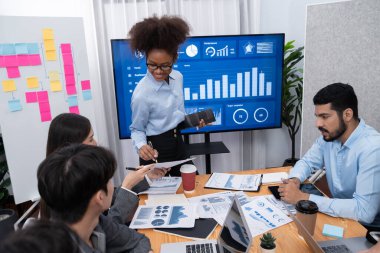 Genç Afrikalı iş kadını modern toplantıda TV ekranında veri analizi paneli sunuyor. Bir grup iş adamıyla konferans odasında iş sunumu. Uyum