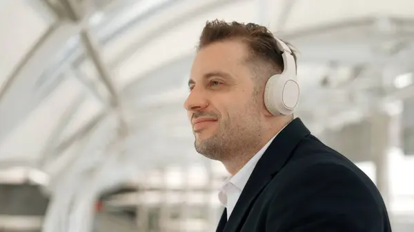 Close up of business man moving his head to music while relaxing listening song from headphones. Caucasian manager wears headset while enjoy listen and move gesture and movement in urban city Urbane.