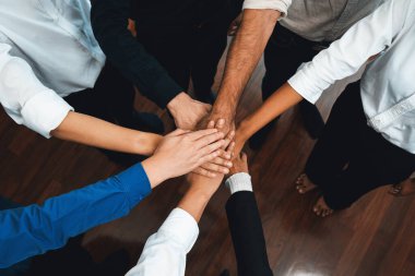 Çeşitli ofis çalışanlarından oluşan bir grup, ofis odasında el ele vererek iş sinerjisini ve iş yerindeki güçlü verimli takım çalışmasını sembolize ediyor. İş çalışanları arasındaki işbirliği ve birlik. Tedbirli