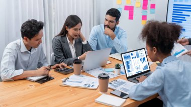 Çok ırklı analist ekibi toplantı masasındaki finansal verileri analiz etmek için BI Fintech yazılımı kullanıyor. Finansal konsol veri ekranında pazarlama göstergesi için analiz edilmiş grafikle birlikte. Uyum