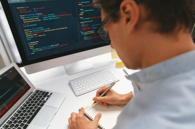 Stresli bilişim geliştiricisi deneme uygulamasında kodlama programı olan bilgisayar ve bilgisayar üzerinde çevrimiçi yazılım geliştirme bilgilerini analiz ediyor. Teknik mühendis önemli not listeleri yazıyor. Bireysel.
