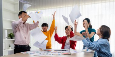 Heyecanlı ve mutlu bir şirket çalışanı başarılı bir iş yaptıktan sonra kutlama yapıp havaya kağıt fırlatıyor. Takım çalışması ve pozitif çevre üretken ve destekleyici bir işyeri yaratır. Sinerjik