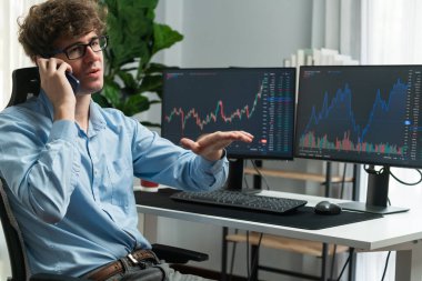 Modern ofiste mevcut pazar grafiğinde dinamik döviz geçmişi olan akıllı telefondan komisyoncuya doğru tartışan genç bir borsa yatırımcısı karmaşık verileri açıklıyor. Toplayıcı.