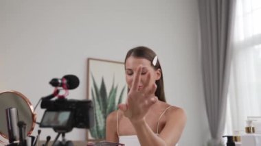 Sosyal medya için güzellik ve kozmetik video içeriği hazırlayan genç bir kadın. Güzellik blogcusu kameraya gülümserken seyircilere ve takipçilere güzellik bakımını gösteriyor. Düzenle