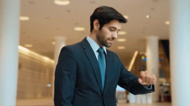 Kafkasyalı zeki iş adamı iş arkadaşını beklerken saate bakıyor. Bulanık geçmişiyle alışveriş merkezinde dikilirken yönetici takım elbise giyiyor. Yatırımcı mavi takım elbise giyer. Sevinçli..