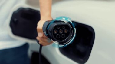 Kameranın önüne odaklanmış EV şarj cihazı fütüristik çevre dostu enerji altyapısı pictogram hologramını gösteriyor. EV araba şarjı sürdürülebilir güç için yenilenebilir enerji kullanıyor. İnceleyin