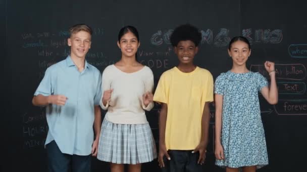 不同的学生举手欢呼和庆祝成功的项目 一群多元文化的孩子站在黑板上 一边拿着工程技术代码一边看着摄像机 — 图库视频影像