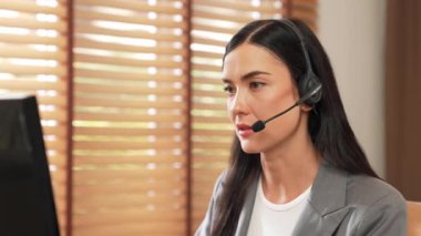 Kadın çağrı merkezi operatörü ya da müşteri hizmetleri çalışanı, müşteriye yardım etmek için kulaklıkla konuşurken çalışma alanı üzerinde çalışıyor. Profesyonel modern iş hizmeti. Blithe