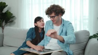 Komik liseli kız masal kitabına işaret ederken mutlu bir baba hikâyesi ve dokunaklı bir jest. Öğrenciler ebeveyn ararken peri kuyruğu hakkında konuşmaktan zevk alırlar. Aile eğlence konsepti. Pedagoji.