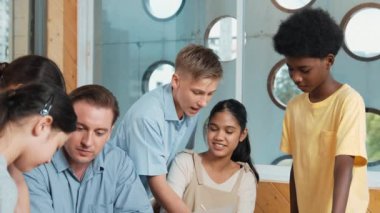 Akıllı robotlar sınıfta dizüstü bilgisayar ekranını işaret ederken, beyaz bir öğretmen yorum yapıyor ya da öğrencilere tavsiye veriyor. Öğretmen bilgisayar kullanırken çeşitli öğrencilerin ders verirken not alması. Öğretim