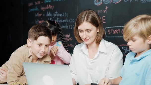 白种人老师用笔记本电脑讲解工程系统 而不同的学生在黑板前拿着电子设备 在Stem课上写着提示或代码 Erudition — 图库视频影像