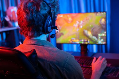 Savaş arenasında çoklu oyunlar takımıyla Moba 'da savaşan genç oyun flamasının sunucu kanalı, neon dijital ışık modern odasındaki arka görüntü ile bilgisayar monitöründe kulaklık takıyor. Toplayıcı.