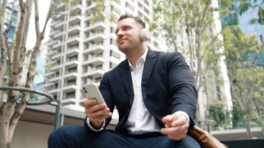 İş adamları, Green City 'deki pazarlama ekibinden gelen satış raporlarını kontrol etmek için telefona bakarken dinlendirici müzik dinlemek için kulaklık takıyor. Happy proje yöneticisi telefon beklerken şarkıya geçiyor. Urbane.