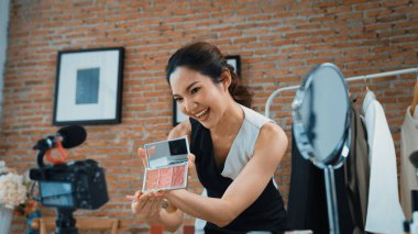 Kadın nüfuzlu kişi canlı yayın yapan video görüntülerini sosyal medya ya da blog üzerinden gözden geçiriyor. Kozmetik stüdyosu ışıklandırmalı mutlu genç kız çevrimiçi pazarlama oturumu yayını için..