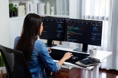 İnternet sitesi uygulamasının kodlama verileriyle birlikte online bilgi yazarak kot gömlek giyen genç Asyalı geliştirici. Güvenlik analizi ile çevrili iki ekran. Taktik.