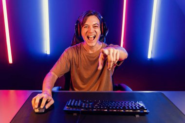 Kazanmak için çevrimiçi oyun oynayan akıllı flama makinesinin sunucu kanalı, neon ışıklı odada seçilen takım yarışması için izleyicilerle birlikte canlı yayında canlı yayında kulaklık takıyor. Bireysel.