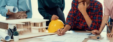 Becerikli mimar takımının tasviri, Mimarlık projesini ev modelleri ve mimari ekipmanlarla toplantı masasında tartışıyor. Yaratıcı tasarım konsepti. - Yakın çekim. Filizlenen.