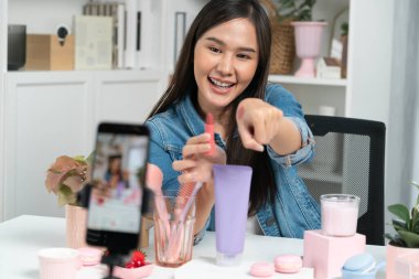 Genç, güzel Asyalı kozmetik makyaj ruju matte pastel rengini modern odadaki sosyal medyada kol testi tanıtımında en çok satanlar listesinde gösteriyor. Taktik.