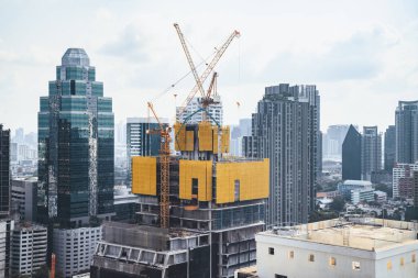 Dış gökdelenlerin, kule vinçleri olan inşaat alanının görüntüsü. İnşaat halindeki şehir manzarası. Binanın tadilatı için çalışan vinçler var. Mavi gökyüzü arka planı. Mimari. Süslü.