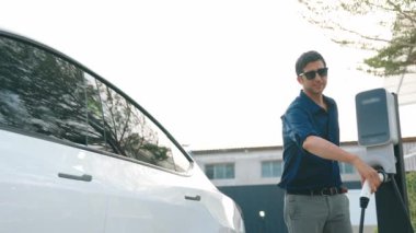 Yavaş çekim çift, alışveriş merkezinin otoparkındaki şarj istasyonundan elektrikli araba aküsünü şarj ediyor. Enerji sürdürülebilir kentsel seyahat yaşam tarzı için şarj edilebilir EV araba