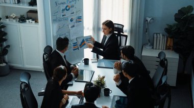 Akıllı yöneticinin üst görünümü, kurul ve kağıt arasındaki grafiği karşılaştırırken aynı zamanda başlangıç projesini iş toplantısında çeşitli takımlardan oluşan bir grupla birlikte planlıyor. Beyin fırtınası yapan ve birlikte çalışan takım. Müdürlük.