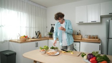 Mutlu baba yemek pişirirken müziğe geçiyor ve modern mutfakta öğle yemeği hazırlıyor. Aktif baba, sebze ve mutfak gereçleri ile çevrili sağlıklı yemek ya da salata yaparken şarkıyla dans ediyor. Pedagoji.