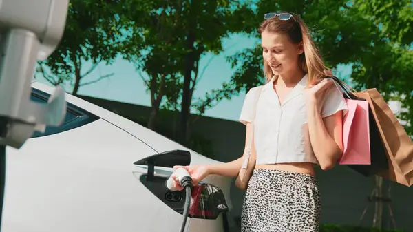 年轻女子乘坐电动车在绿色可持续城市室外花园充电 电动车内置车绿色清洁充电能的城市可持续生活方式 — 图库照片