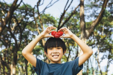 Eco awareness campaign promoting environmental protection with happy asian boy holding heart as symbol of love for nature and ecology for future greener sustainable Earth. Gyre clipart