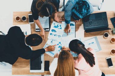 Modern ofisteki iş adamları ve iş kadınlarıyla grup toplantısındaki iş adamlarının en üst düzey görüşü, masada dizüstü bilgisayar, kahve ve belge ile. Kurumsal şirketler uds