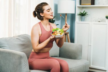 Spor giyimli sağlıklı ve vejetaryen bir kadın bir kase meyve ve sebzeyle. Sağlıklı beslenme ve spor için vejetaryen yaşam tarzı ev konseptinde vücut fiziği.