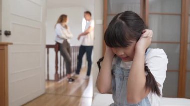 Stresli ve mutsuz genç kız köşeye kıvrılıp kulaklarını kapatarak arka planda ebeveyninin tartışmasını engelliyor. Evde aile içi şiddet ve travmatik çocukluk depresyona dönüşür. Titiz
