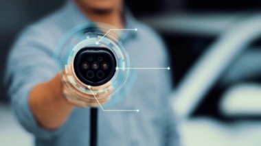 Kameranın önüne odaklanmış EV şarj cihazı fütüristik akıllı dijital EV batarya durum hologramını gösteriyor. EV araba şarjı sürdürülebilir güç için alternatif enerji kullanıyor. İnceleyin