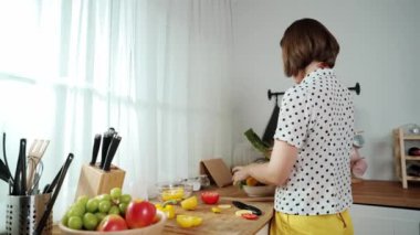 Kafkaseli anne kahvaltıda sebze pişirirken mutlu anne de modern mutfakta salata için taze malzemeler hazırlıyor. Hizmetçi sağlıklı yemek pişiriyor. Dikkat konsepti. Pedagoji.