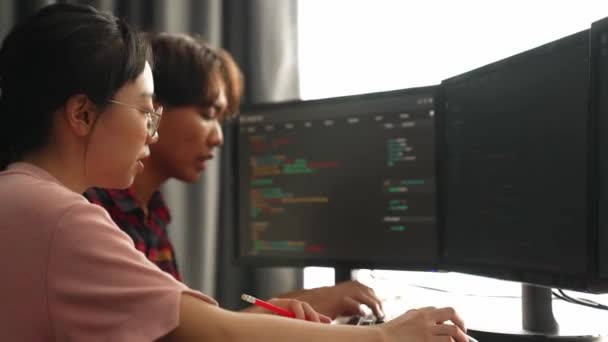 コンピュータプログラミングのためのバックエンドソフトウェア開発エンジニアは コンピューティングコードをデバッグし オフィスのモニターに表示される複雑なアルゴリズムを解決します バージョニング — ストック動画