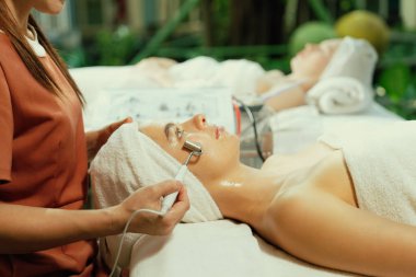 Güzeller güzeli beyaz kadın güzellik teçhizatı ve tıbbi ekipmanlarla çevrili modern kaplıca salonundaki profesyonel eller tarafından masaj yaptırırken spa yatağında uzanıyor. Kapatın. Huzur