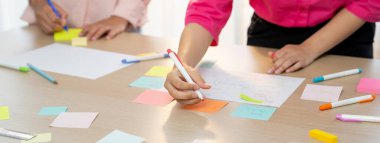 Bir grup genç iş adamı renkli yapışkan notlar hakkında fikir üretiyor. İş yerindeki toplantı odasında yapışkan bir nota yazarken başlangıç grubunun pazarlama stratejisinin portresi. Değiştirilmiş.