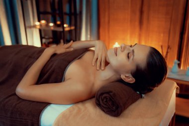 Beyaz kadın müşteri stres önleyici spa masajının keyfini çıkarıyor ve lüks otel ya da otelde sıcak mum ışığında güzellik teniyle eğleniyor. Sessiz.