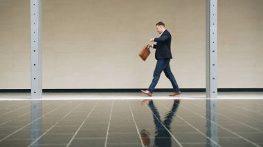 İş adamının iş yerine giderken tren istasyonuna yürürken saatine bakması. Akıllı Kafkas yöneticisi modern şehir boyunca yürümek ve buluşmak için zamanı kontrol ediyor. Urbane.