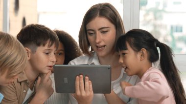 Bir grup öğrenciye çevrimiçi ders verirken elinde tablet tutan akıllı öğretmen. Yetenekli eğitmen mühendislik derslerini anlatırken genç öğrenci oturuyor ve sunumu dinliyor. Etkinlik.