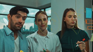 Profesyonel iş adamları beyin fırtınası yapıyor, fikir paylaşıyor, düşünüyor yetenekli erkek liderler cam duvarda yapışkan notlar yazarken. Yetenekli yönetici ofisteki cam duvara iş planı koymuş. İzleme