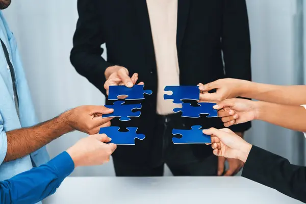 Business team joining jigsaw puzzle together symbolize group of business partnership and strong collective unity teamwork in problem solving solution for business success. Prudent