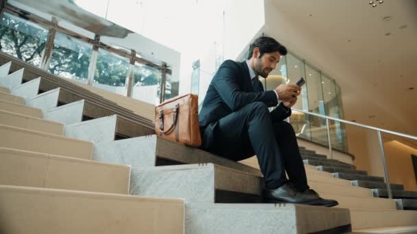Улыбаясь Опытный Бизнесмен Играет Телефон Сидя Лестнице Молодой Профессиональный Менеджер — стоковое видео