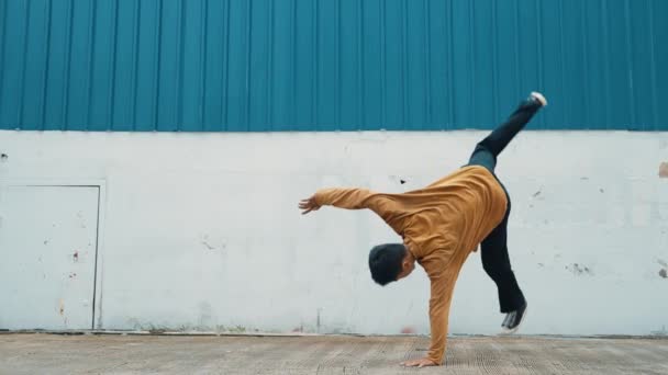 ヒスパニック系男性が壁の前で腕を伸ばし 踊るストリートダンス ヒップホップスタイルでボーイダンスを練習するカジュアルな衣装でダンサーや振付師のモーションショット アウトドアスポーツ 2024 ヒップホップ — ストック動画
