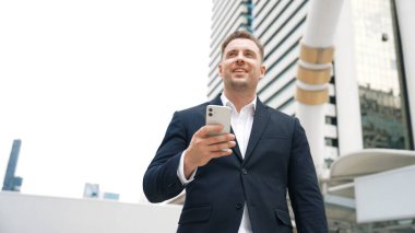 Kafkasyalı iş adamı şehir merkezinde dururken cep telefonlarını kontrol ediyor ve pazarlama ekibinden satış raporlarını inceliyor. Yetenekli bir yönetici cep telefonu üzerinde çalışıyor ve veri analizine bakıyor. Urbane.