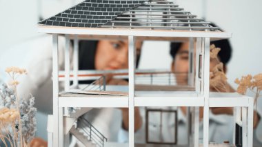 Ev modeli yapısını ölçmek için birlikte çalışan kooperatif mühendisi kapatın. Genç ve güzel mimar ev modelini ölçerken erkek mühendis performansını destekliyor. Tertemiz..