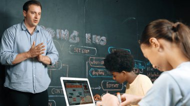 Kafkas öğretmeni alkışlayarak öğrencileri kodlamayı veya programlamayı teşvik etmek için alkışlıyor. Çeşitli öğrenciler STEM sınıfına katılırken başarılı bir projeyi kutlamak için el çırpıyorlar. Öğretim.