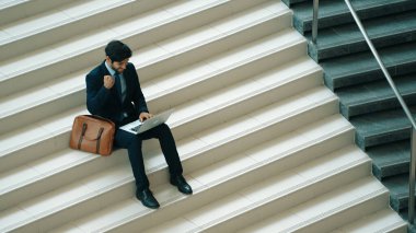 Üst düzey bir iş adamı merdivenlerde otururken başarılı bir projeyi kutluyor. Akıllı proje yöneticisinin yeni bir iş bulması, terfi alması, bilgisayar kullanarak arkadaşlarını arayarak satışları artırması. Sevinçli..