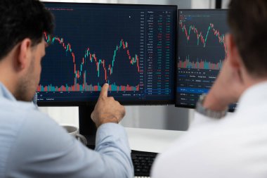 Moda grafiğinin dinamik veritabanını göstermek için akıllı telefon ve bilgisayar kullanarak kahve içerken iş arkadaşıyla ciddi yüz paylaşımı yapan yatırımcı hisse senedi ticareti. Monitör yatırım değişimi gösteriyor. Satılabilir.